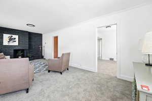 Living area featuring carpet, ornamental molding, and a fireplace