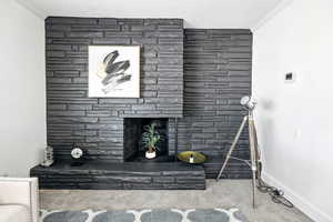 Detailed view of crown molding, carpet flooring, and a fireplace