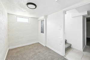 Basement featuring a textured ceiling, carpet, and stairway