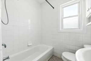 Bathroom featuring tile walls, tub / shower combination, and tile patterned floors
