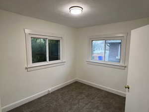 Unfurnished room with dark colored carpet and a textured ceiling