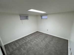 Basement with dark carpet and baseboards