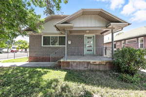 Rear view of property featuring brick siding, a porch, and a lawn