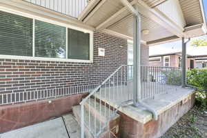 Doorway to property with brick siding, board and batten siding, and covered porch