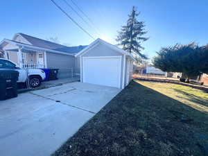 View of home's exterior featuring a garage, driveway, an outbuilding, and a shingled roof
