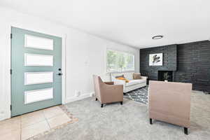 Carpeted living area featuring a fireplace, ornamental molding, and tile patterned flooring