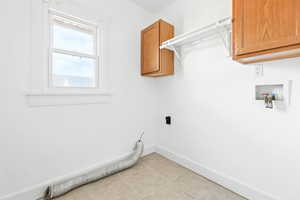 Washroom featuring cabinet space, hookup for an electric dryer, washer hookup, and light tile patterned flooring