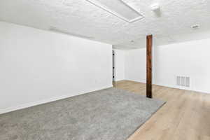 Below grade area with light wood-style floors and a textured ceiling