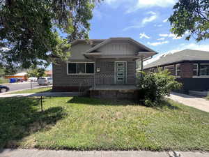 View of front facade with covered porch, a front lawn, and brick siding