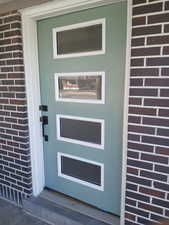 Doorway to property featuring brick siding
