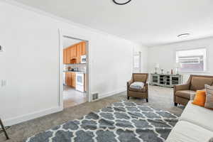 Living area featuring light colored carpet, crown molding, and light tile patterned floors