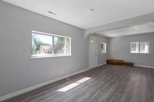Unfurnished room with dark wood-style floors, arched walkways, plenty of natural light, and a textured ceiling