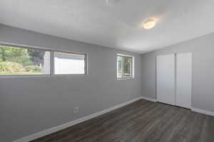 Unfurnished bedroom featuring a textured ceiling, dark wood finished floors, a closet