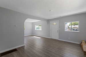Entryway featuring arched walkways, a textured ceiling, and dark wood-style flooring