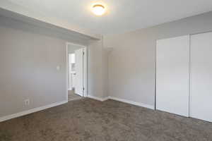 Unfurnished bedroom with carpet, a textured ceiling, and a closet