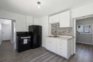 Kitchen with black appliances, a textured ceiling, white cabinetry, dark wood finished floors, and tasteful backsplash