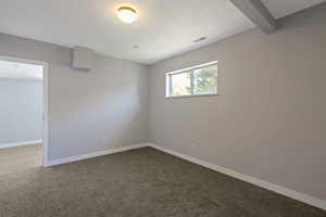 Empty room with dark colored carpet and a textured ceiling