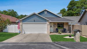Ranch-style home with a garage, driveway, covered porch, brick siding, and a shingled roof