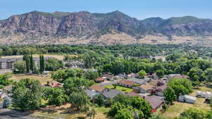 Aerial view of property and surrounding area with a mountain backdrop and nearby suburban area