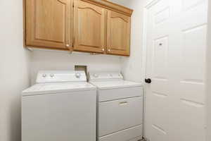 Washroom with washer and clothes dryer and cabinet space