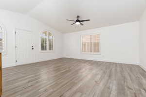 Unfurnished room with a ceiling fan, light wood-style flooring, and vaulted ceiling
