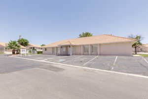 Ranch-style house featuring uncovered parking, a tile roof, and stucco siding