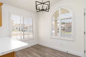 Unfurnished dining area featuring plenty of natural light, light wood-style flooring, and a chandelier