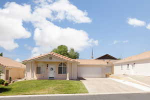 Mediterranean / spanish-style home with a tile roof, an attached garage, stucco siding, concrete driveway, and a front lawn