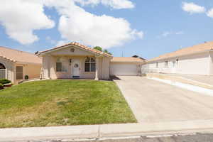 Mediterranean / spanish-style house featuring a tiled roof, driveway, stucco siding, an attached garage, and a front yard