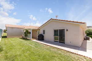 Rear view of property with a patio, stucco siding, and a lawn