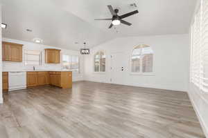 Unfurnished living room featuring lofted ceiling, a chandelier, ceiling fan, and light wood-style floors