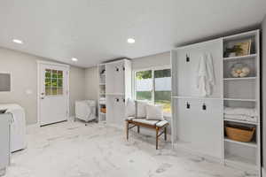 Laundry area with washer / clothes dryer, a textured ceiling, light marble finish floors, recessed lighting, and healthy amount of natural light