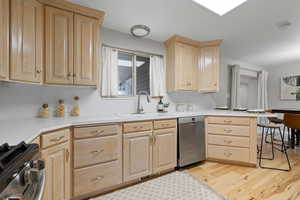 Kitchen featuring light brown cabinetry, stainless steel appliances, light wood-style floors, and light countertops