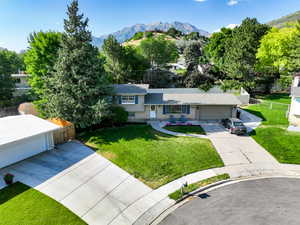 Split level home featuring concrete driveway, a mountain view, a garage, and roof with shingles