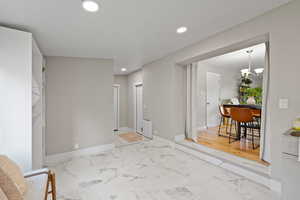 Unfurnished room featuring recessed lighting, light marble finish floors, and a chandelier