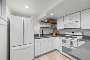 Second Kitchen with white appliances, dark countertops, white cabinets, light wood-style floors, and recessed lighting