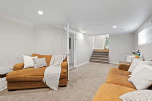 Living area with carpet flooring, stairs, and recessed lighting