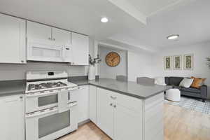 Second Kitchen with white appliances, a peninsula, dark countertops, open floor plan, and white cabinets