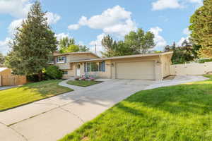 Split level home with a garage, a gate, and concrete driveway