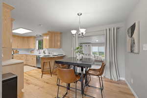 Kitchen featuring light brown cabinets, light wood-style flooring, a chandelier, light countertops, and healthy amount of natural light