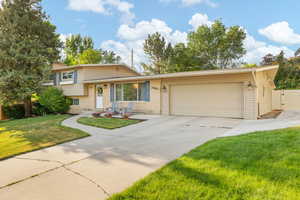 Split level home with a garage, brick siding, and driveway