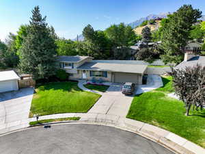 Split level home featuring an attached garage, a mountain view, concrete driveway, roof with shingles, and brick siding