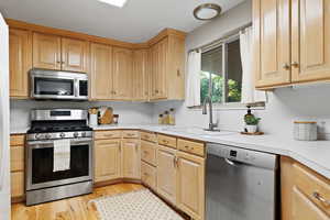 Kitchen featuring appliances with stainless steel finishes, light countertops, light wood-style flooring, and light brown cabinetry
