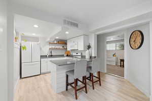 Second Kitchen featuring white appliances, dark countertops, open shelves, light wood-style flooring, and recessed lighting