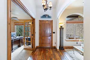 Foyer entrance with arched walkways, hardwood / wood-style flooring, and a chandelier