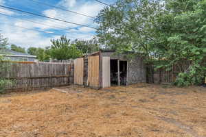 Fenced backyard featuring a storage unit
