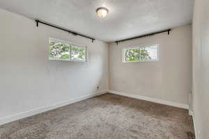 Carpeted spare room featuring baseboards and a textured ceiling