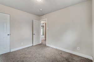 Carpeted empty room featuring baseboards and a textured ceiling
