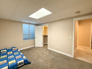 Unfurnished bedroom featuring carpet and a drop ceiling