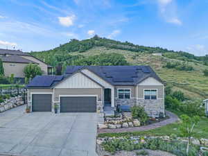 View of front of house with board and batten siding, a garage, concrete driveway, stone siding, and roof mounted solar panels